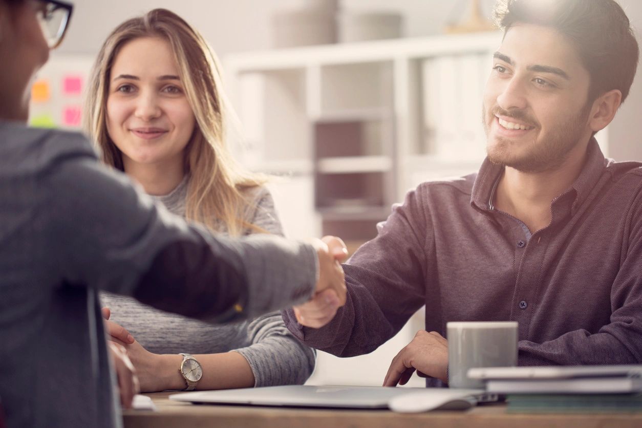 Two people smiling during handshake at meeting